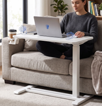 Person using a laptop on a white adjustable desk in a living room setting.